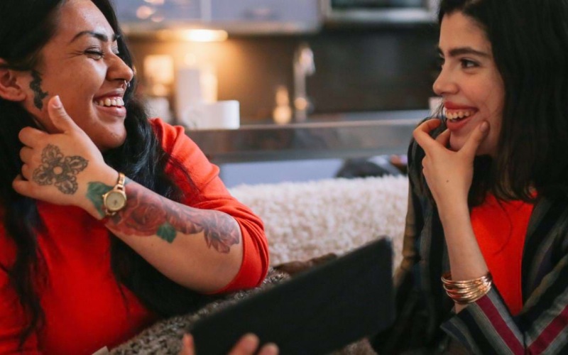 a couple of women sitting on a couch and laughing